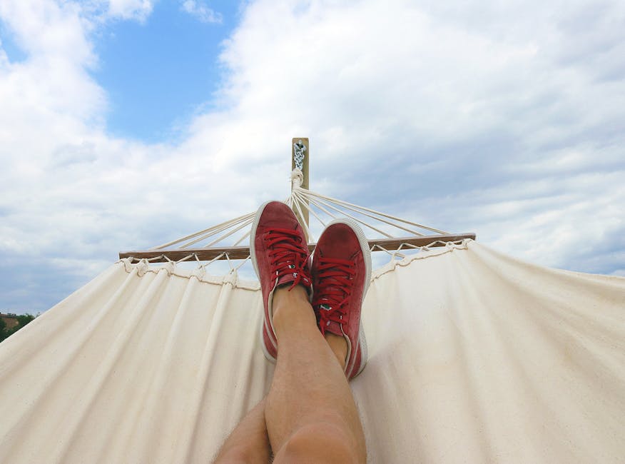 pexels-photo-914929-914929 Feet resting on a hammock with red sneakers, epitomizing summer relaxation and leisure outdoors.